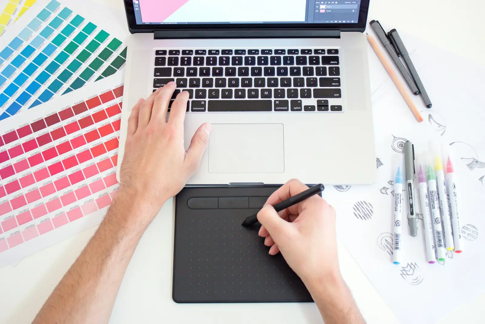 Designer working on a drawing tablet beside colour swatches