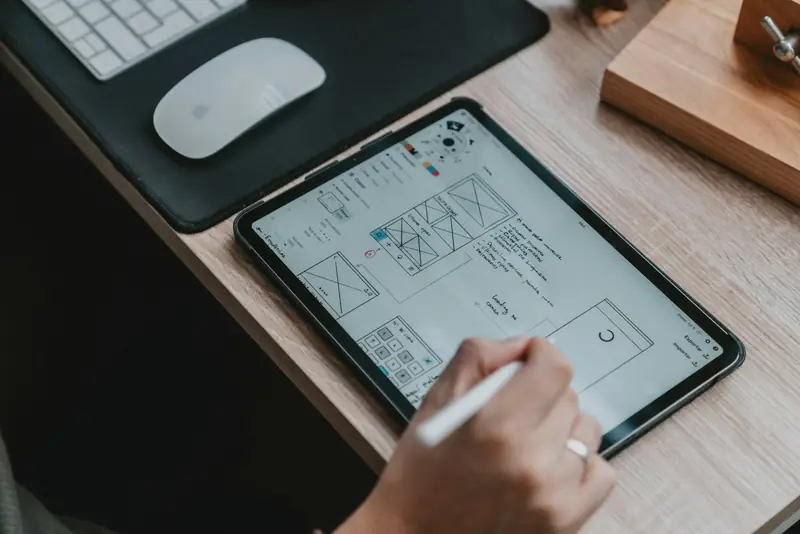 Designer sketching website wireframes on a tablet at a desk