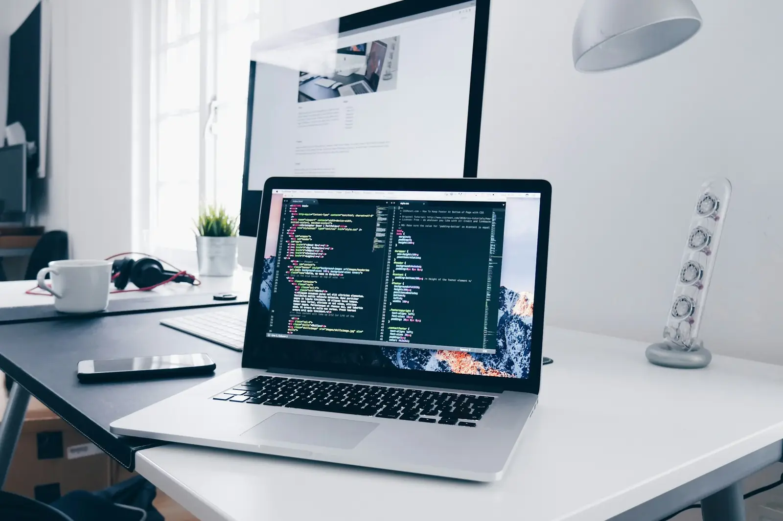 Laptop on a bright desk showing website code during development